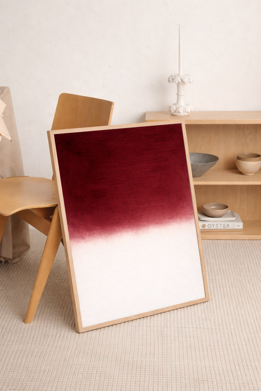 Framed artwork with a gradient from red to white on a wooden stand in a room setting.